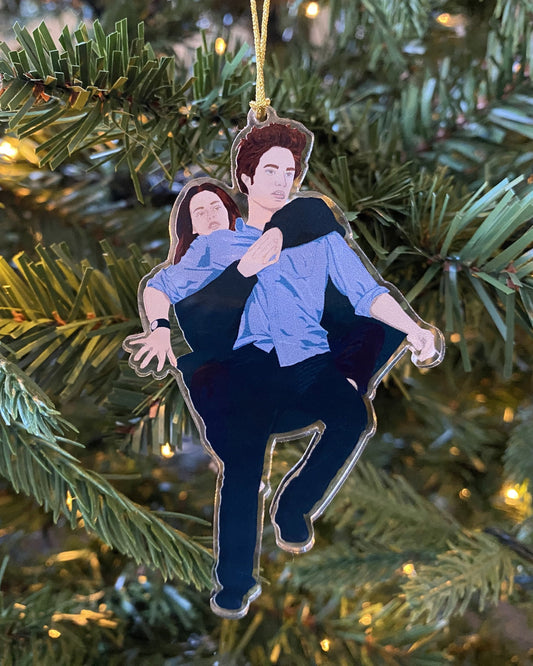 A Twilight inspired Christmas tree ornament featuring an illustration of Edward Cullen and Bella Swan, hanging on a Christmas tree with a gold cord.